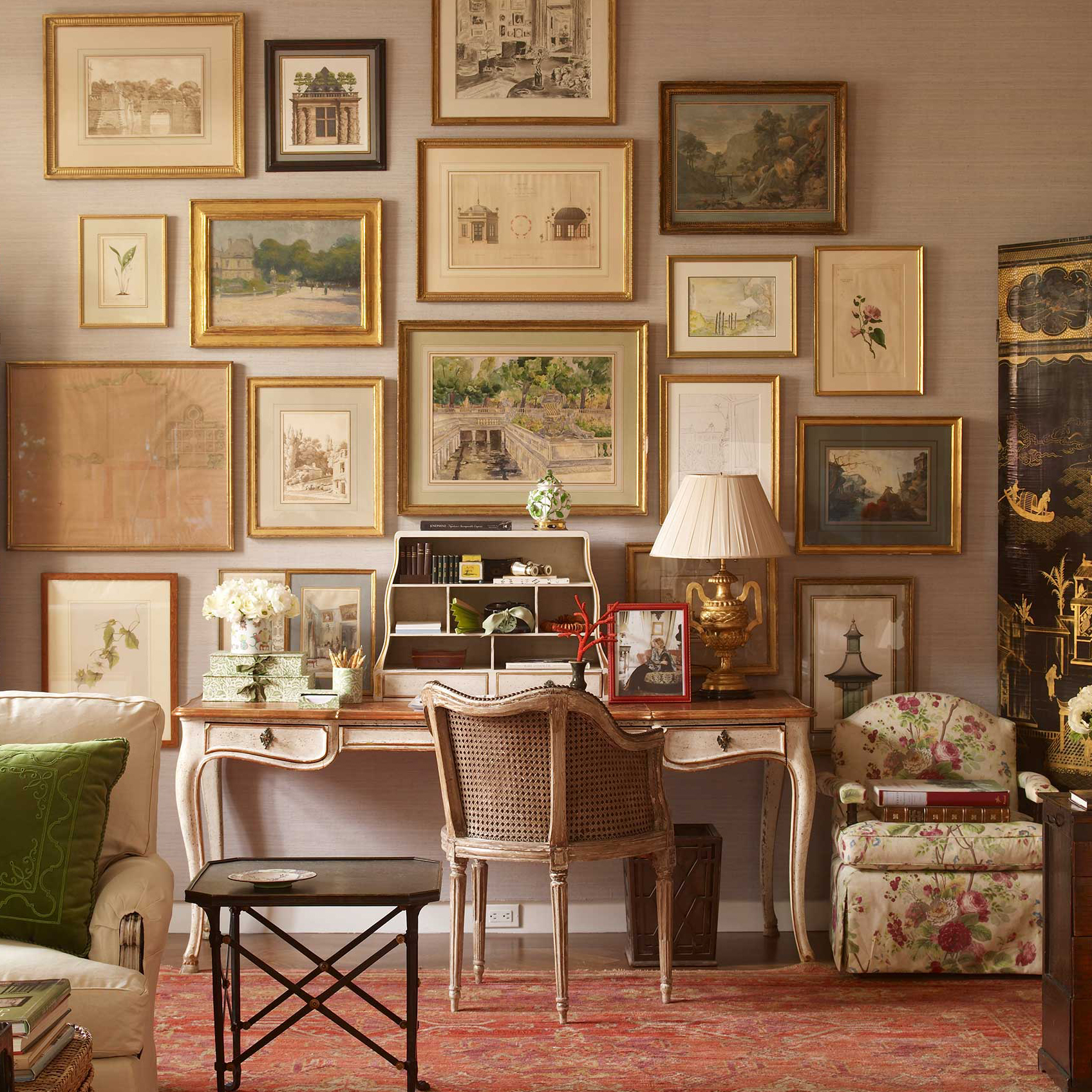 A contemporary bedroom interior decorated with classical furnishings and gold-framed artworks hung salon style.