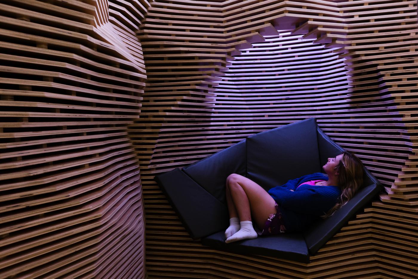 Student lying down and relaxing in wood installation