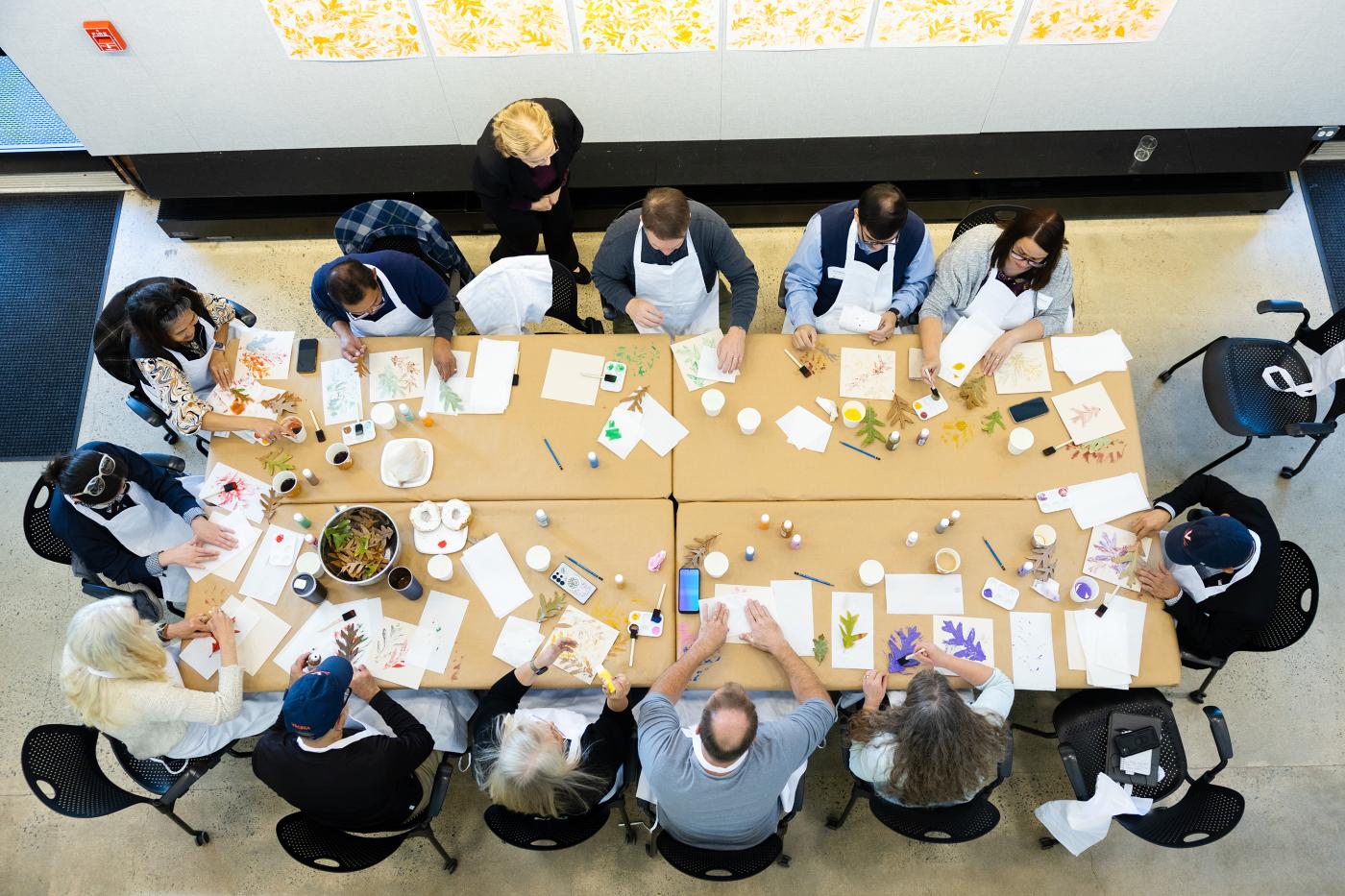 bird's eye view of a group of people seated at large table making art