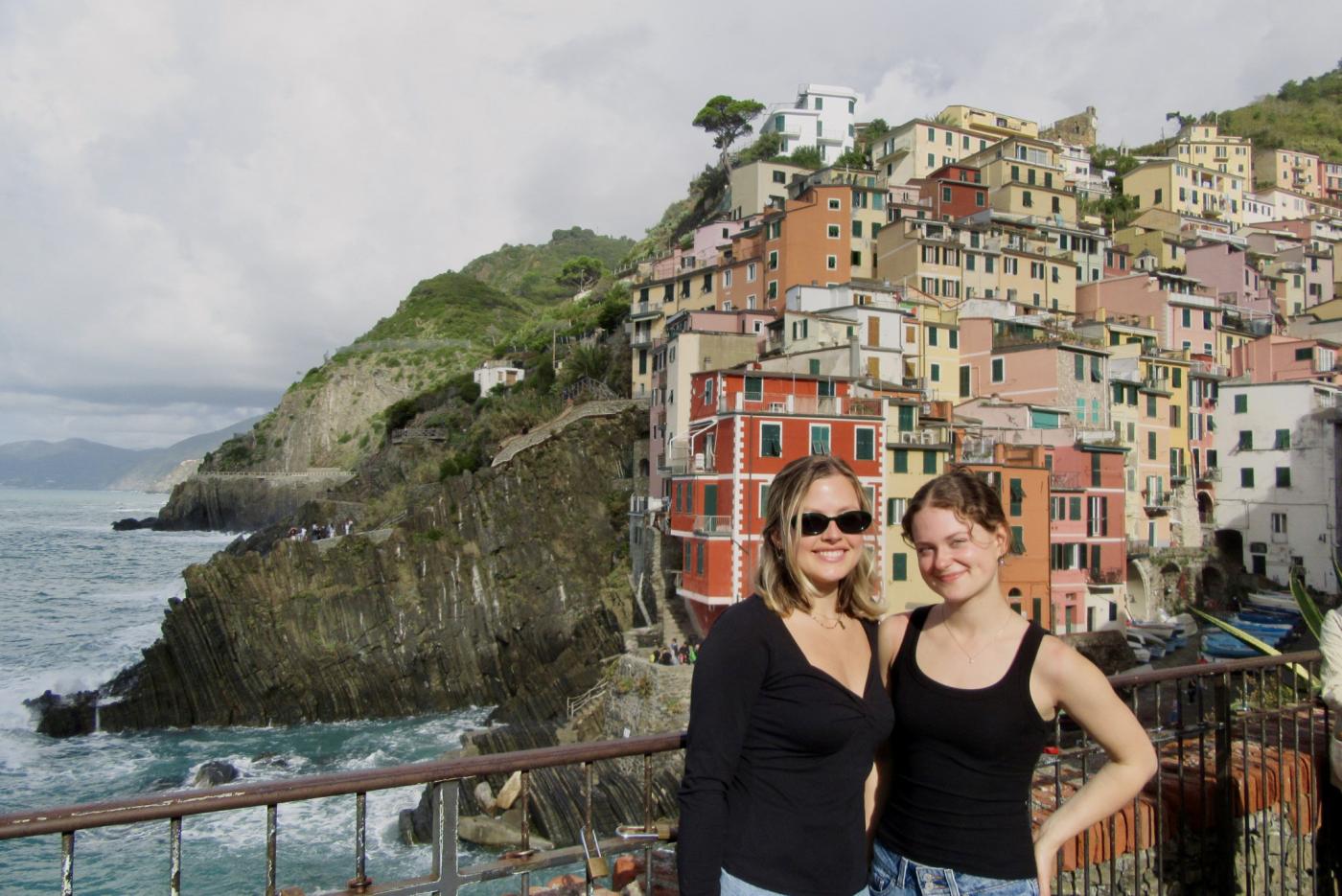 Venice Studio Candid Fall 2025 - Rena and friend in front of town on cliff by waterside