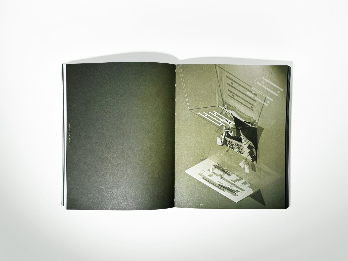 An open book showing olive green pages. The left page is blank and the right page has a spatial diagram of an abstract structure.