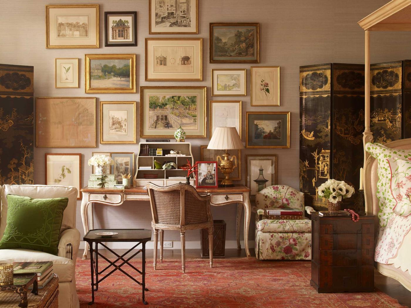 A green-hued sitting room and bedroom space featuring a dramatic gallery wall with artworks in gilded frames.