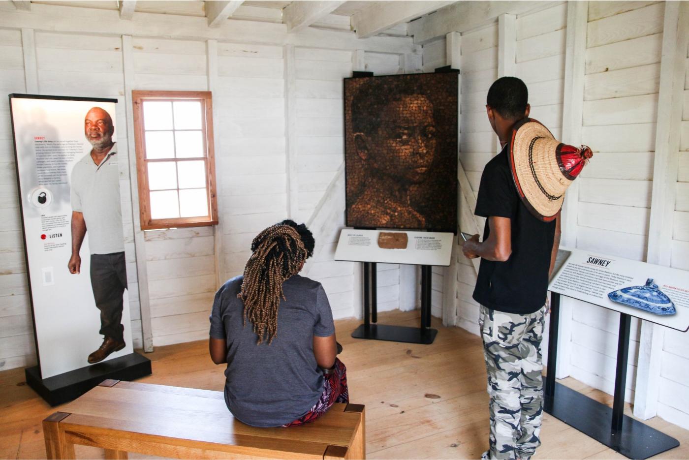 Two people viewing an installation about the stories of the enslaved laborers at Montpelier. 