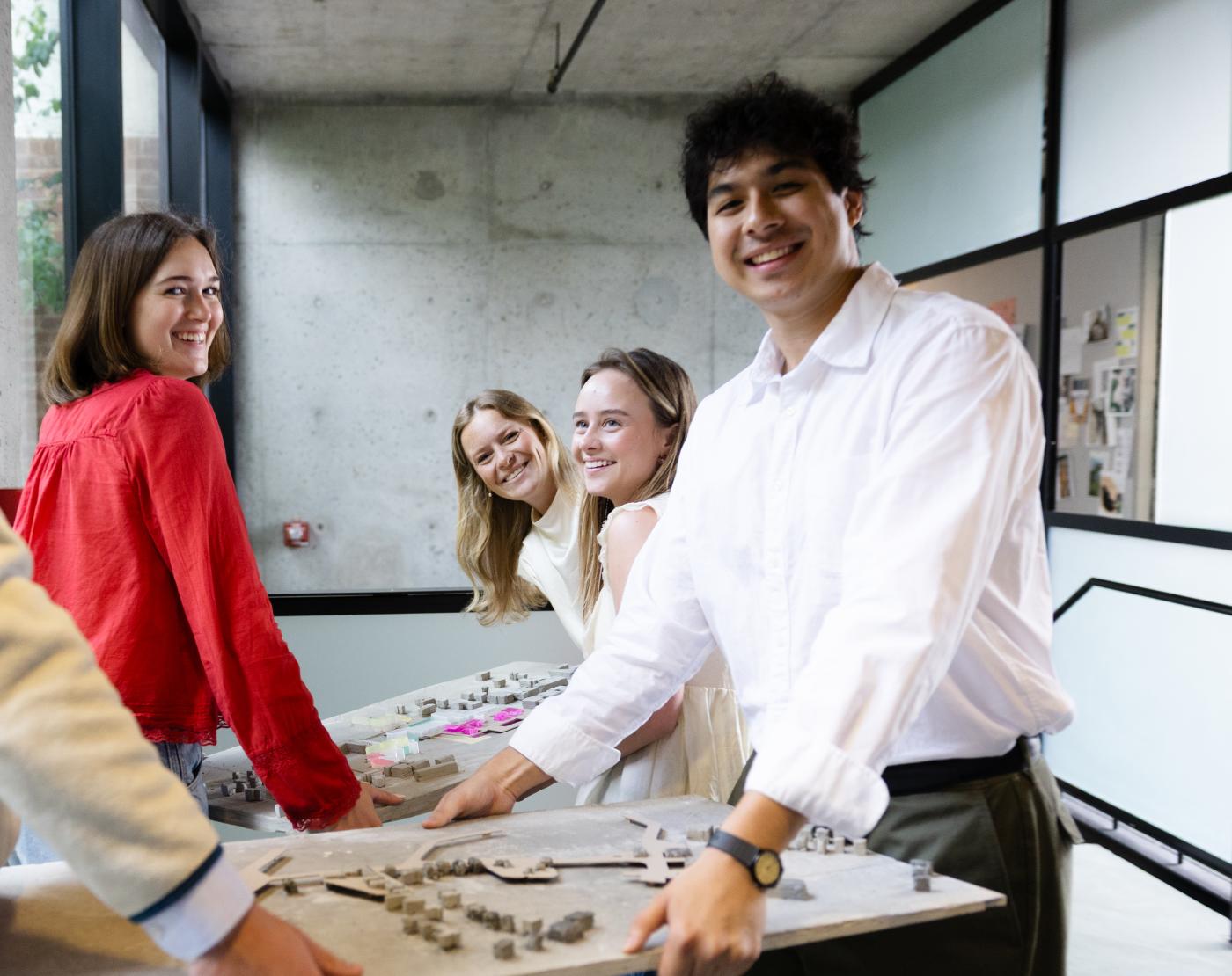 Four students helping each other carry an architectural model